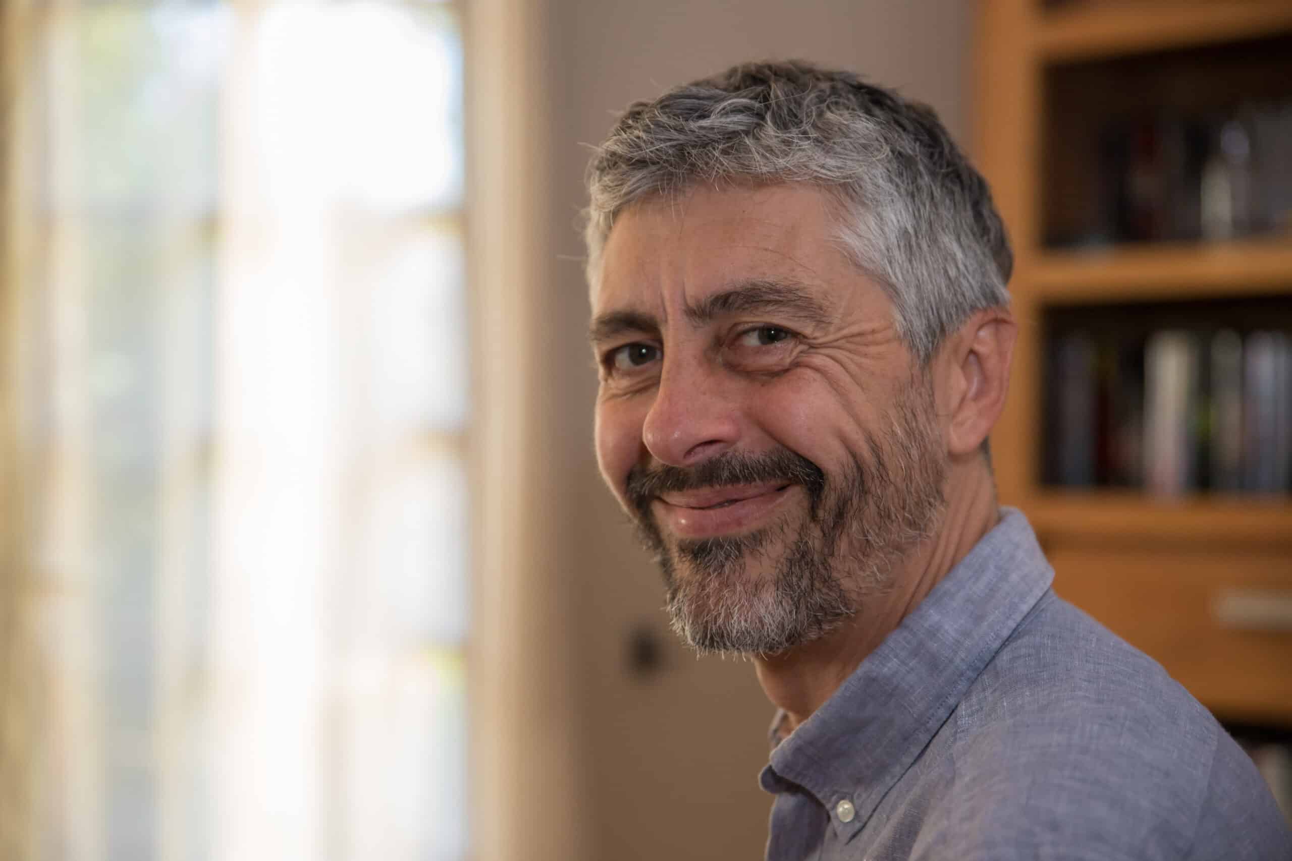portrait d'un homme de 50 ans souriant. Il travaille chez lui sur son ordinateur